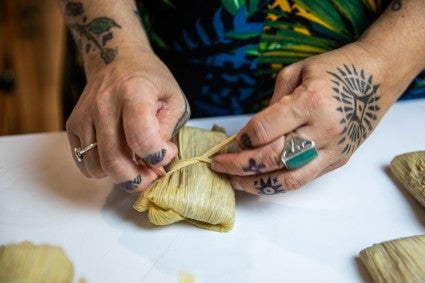 Hands tying corn husk around Cherokee Bean Bread